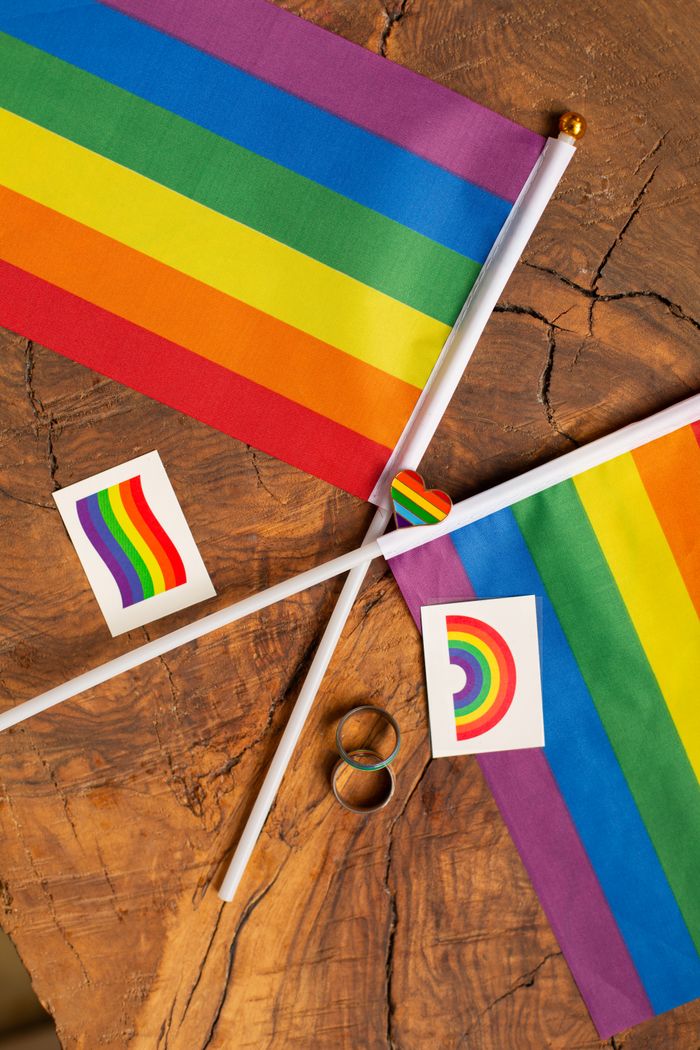 Rainbow pride flags and symbols arranged on a rustic wooden table, representing LGBTQ+ pride and unity.