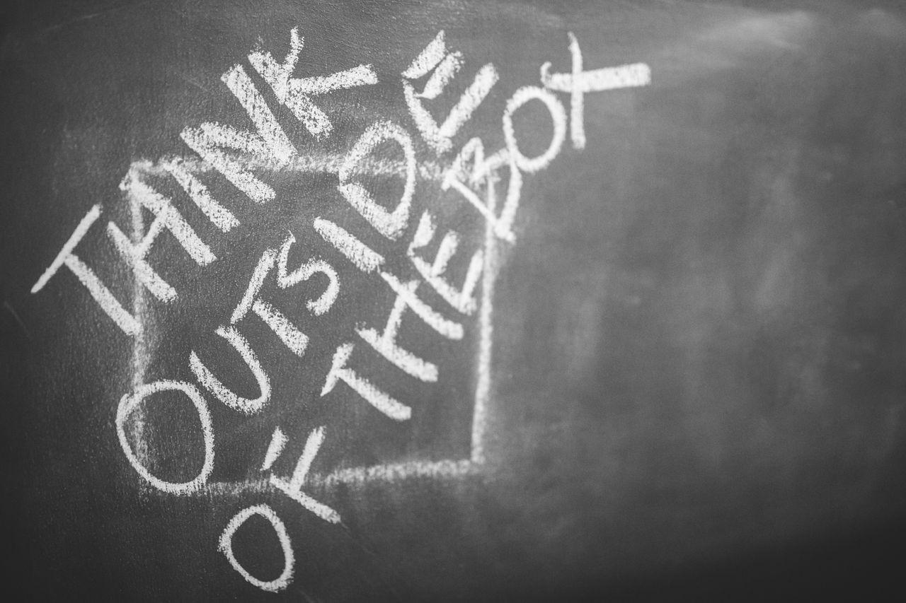 Chalkboard with 'Think Outside the Box' handwritten, inspiring creativity.